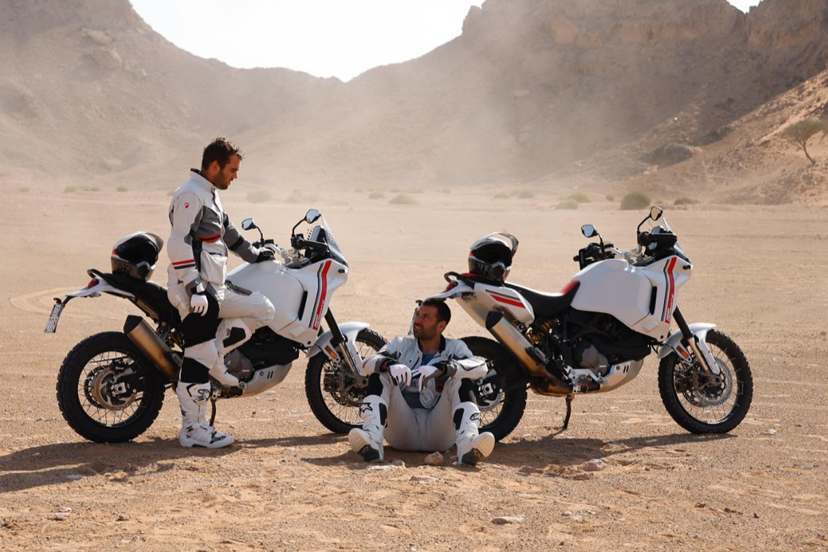 Antoine Meo y su compañero descansan después de poner a prueba la Ducati Desert X en el desierto de Abu Dabi